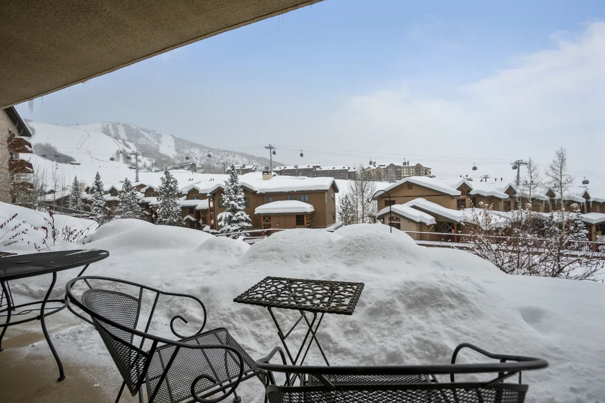 A panoramic winter landscape showing a snow-covered outdoor seating area, mountain views, and distant cable cars. The scene conveys easy access to slopes and outdoor adventures, as well as opportunities to relax together after a day out.