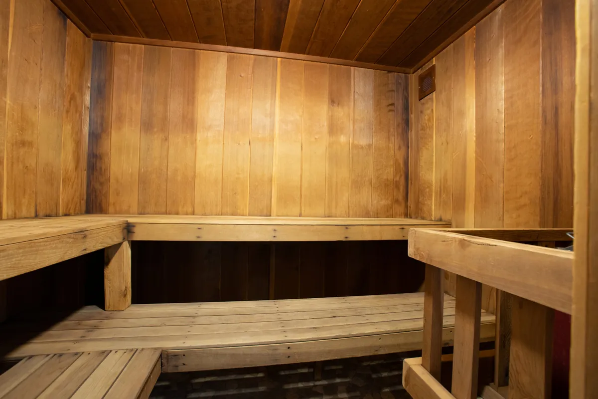 A calming sauna room lined with wood and equipped with comfortable benches, designed for relaxation and wellness. The environment is warm, meditative, and inviting.